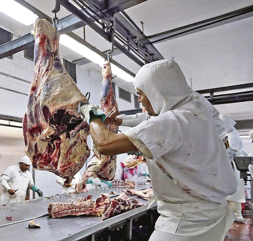 Workers handle beef carcasses at the Ecocarne Meat Plant slaughterhouse in San Fernando