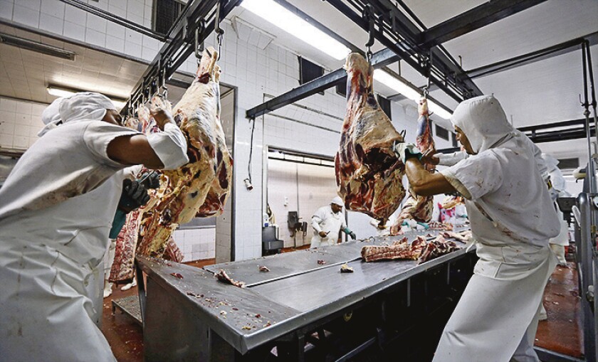 Workers handle beef carcasses at the Ecocarne Meat Plant slaughterhouse in San Fernando