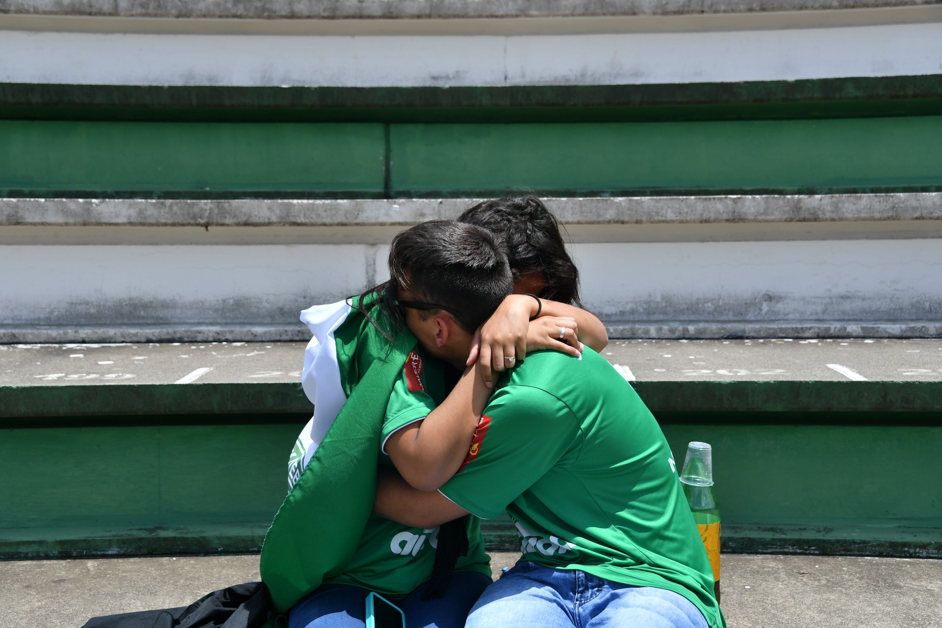 Dos personas se abrazan durante el tributo al club brasileño Chapeconese. Foto: AFP