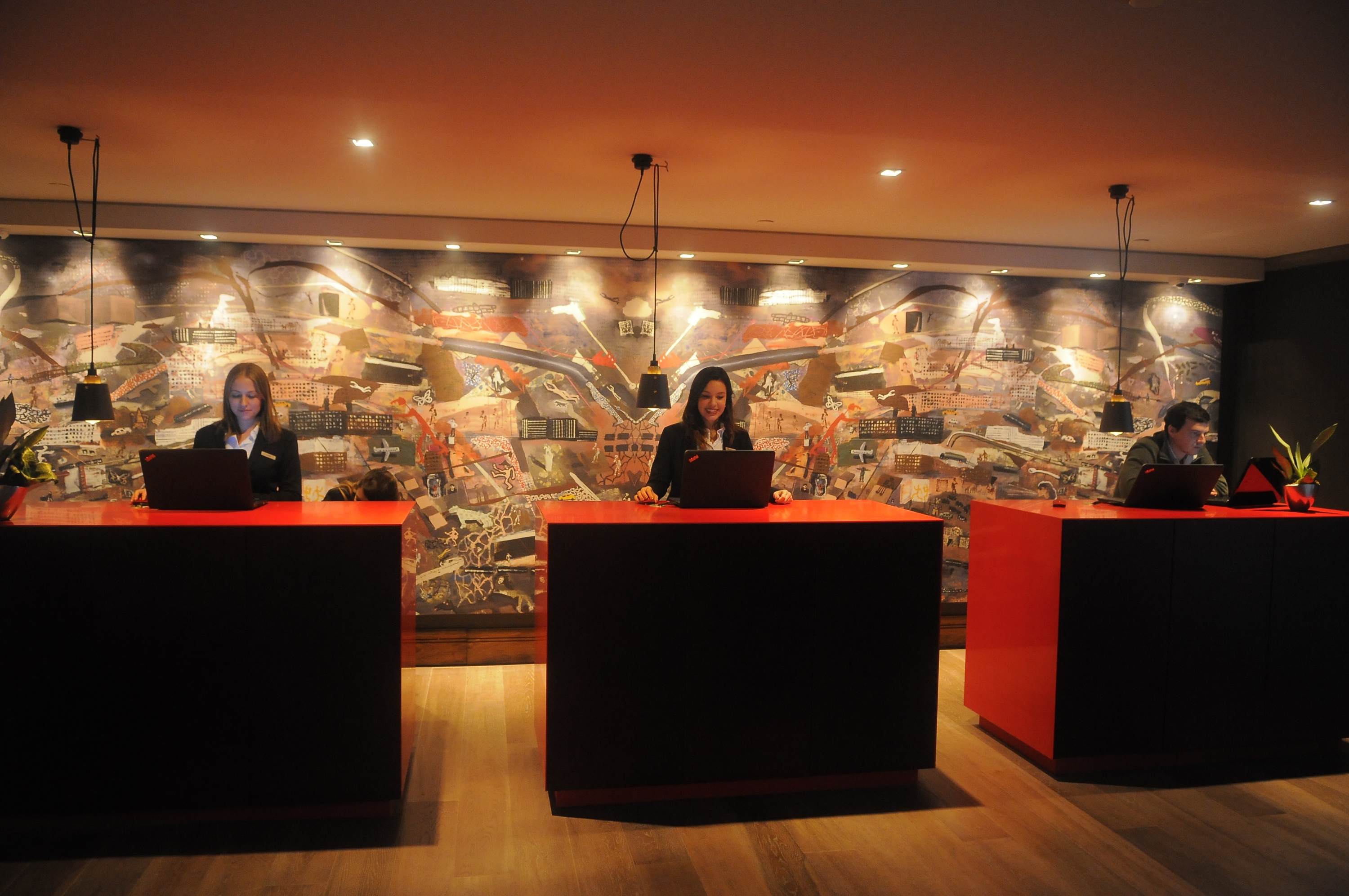 La recepción del hotel con escritorios separados y un mural de Ignacio Iturria de fondo.