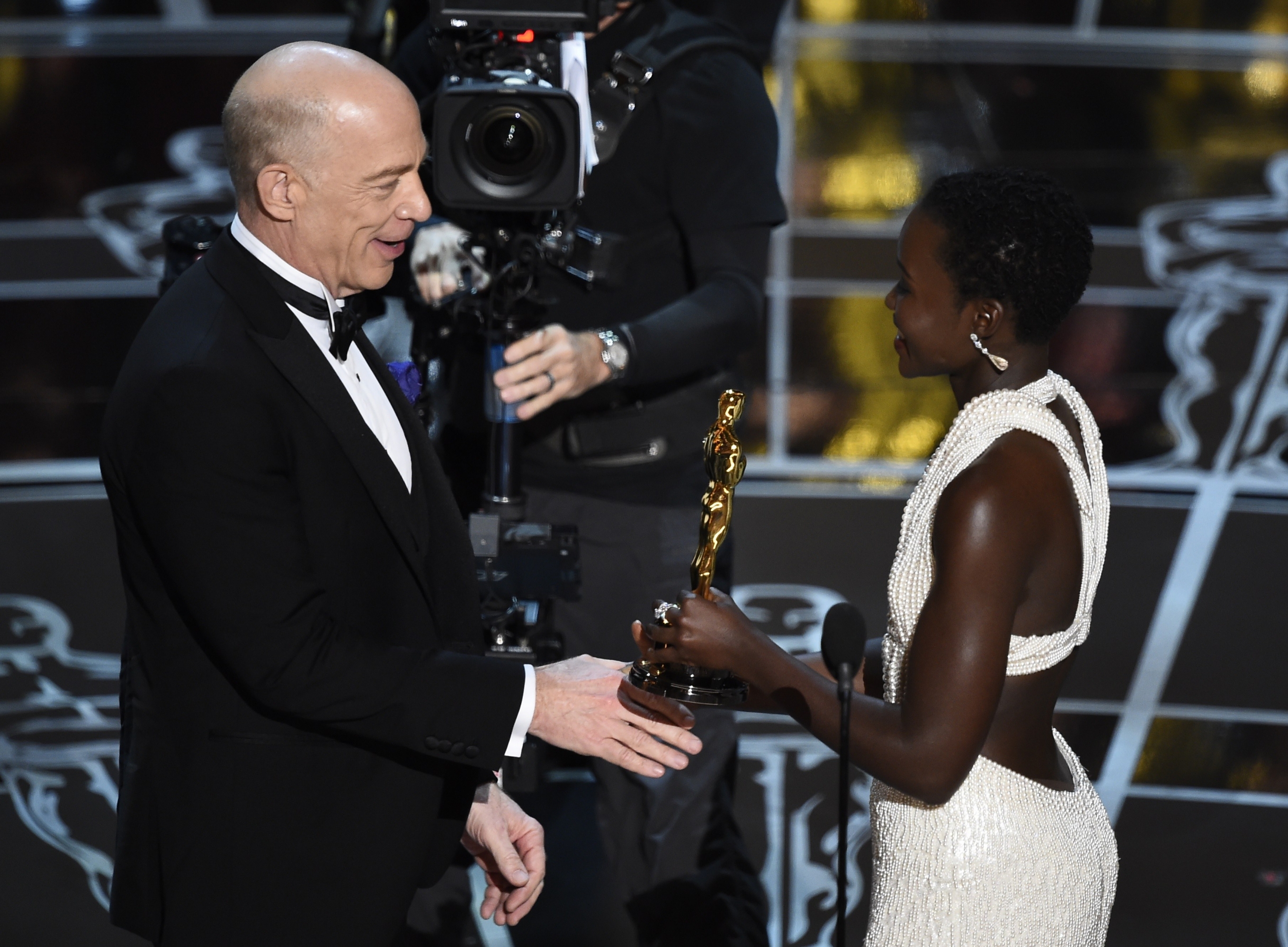 Actress Lupita Nyong'o le entrega el premio a mejor actor secundario a J.K. Simmons. Foto: AFP
