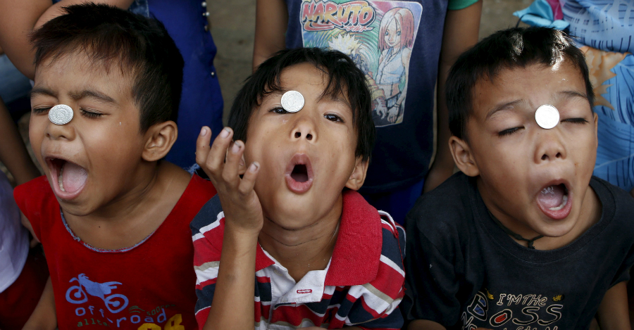 Niños filipinos juegan con monedas durante la tradicional celebración de Nuestro Señor Jesucristo en Quezón, Filipinas. Foto: Reuters.