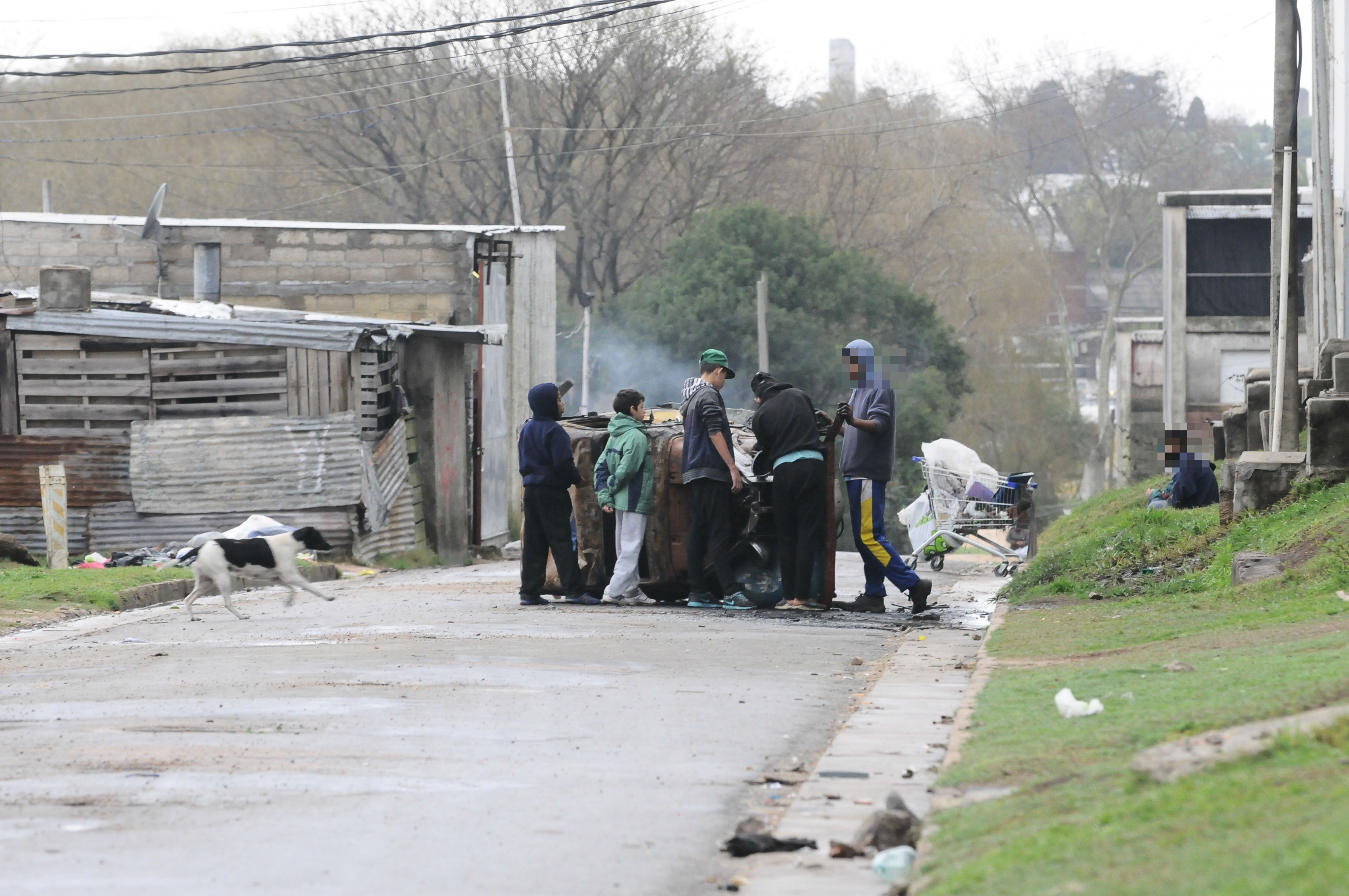 En el asentamiento, jóvenes desguazan auto. Cerca, un carrito de supermercado. Foto: D.Borrelli.