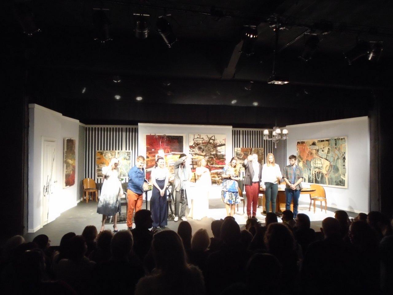 El elenco completo saludando al público que aplaude de pie.