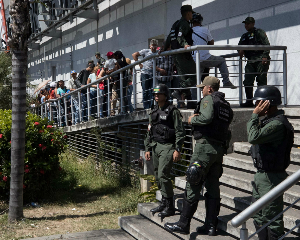 Bajo una fuerte vigilancia, venezolanos esperan afuera de un supermercado. Foto: EFE