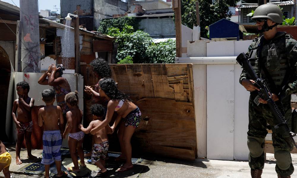 Algunos niños se refrescan en una ducha en la vereda mientras el operativo se desarrolla. Foto: AFP