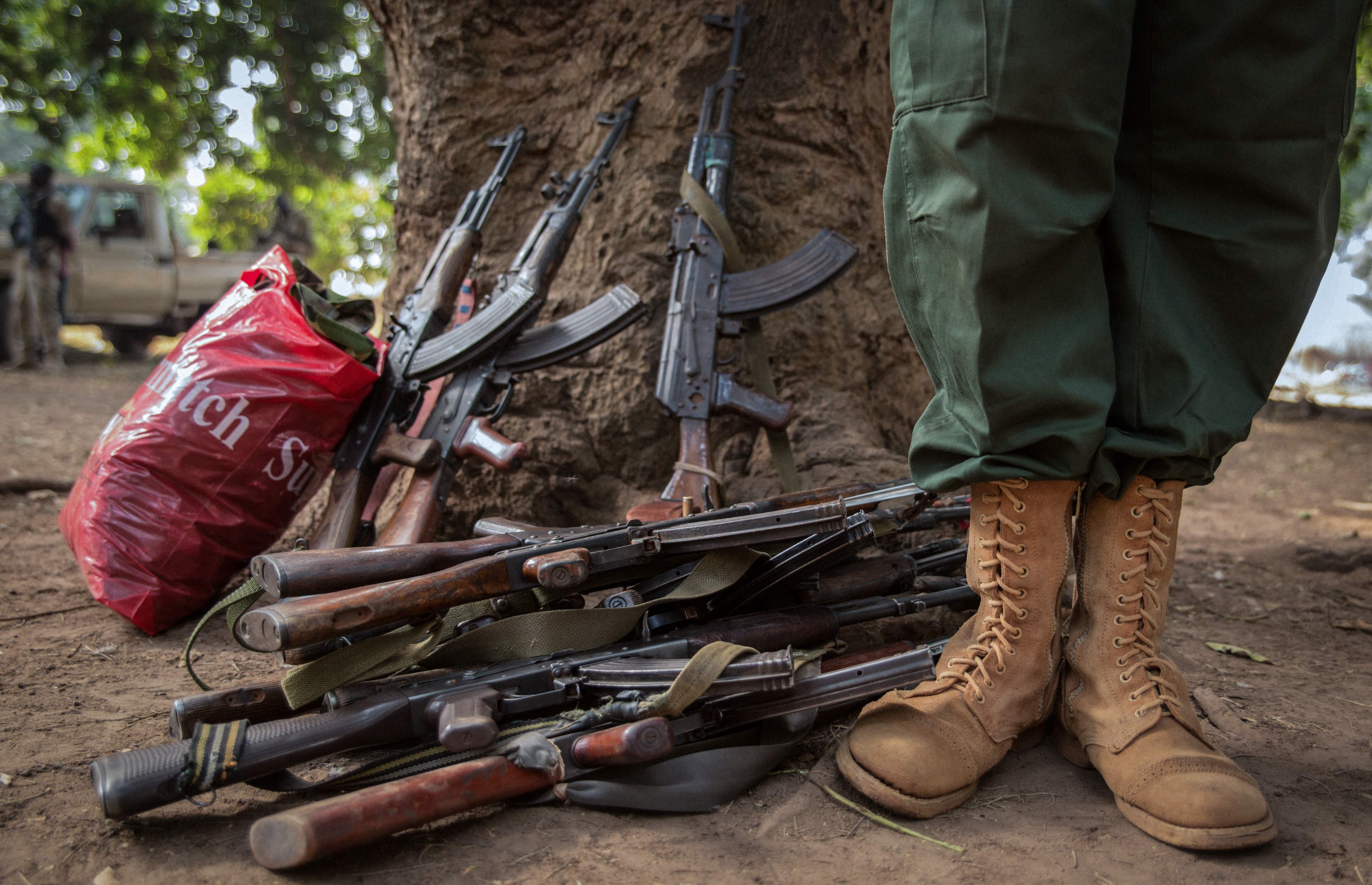 Un joven se para junto a las armas de los soldados liberados. Foto: AFP