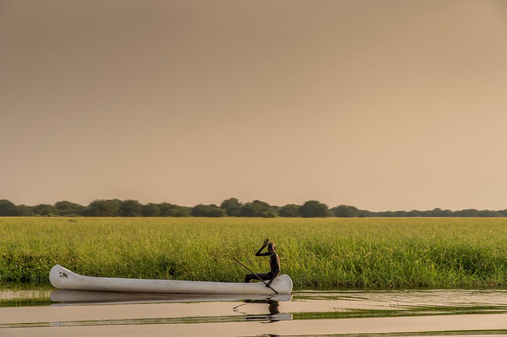 Un hombre mayor va a buscar sus redes de pesca con su bote en el río Pibor ©Frederic NOY