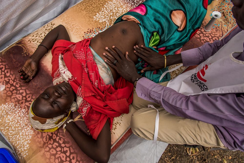 Personal médico de MSF examina a Nyarvotjoack, de 19 años, durante una clínica móvil en la aldea de Meer ©Frederic NOY