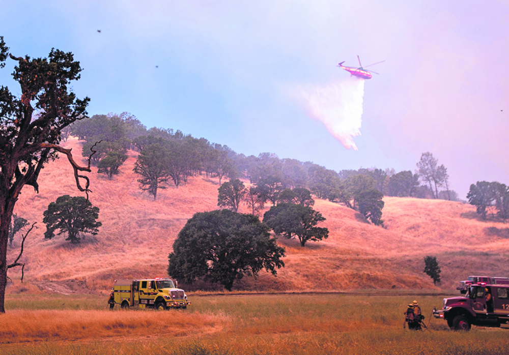 Combate: un helicóptero lanza agua en la zona de Clear Oaks, en el estado de California. Foto: AFP