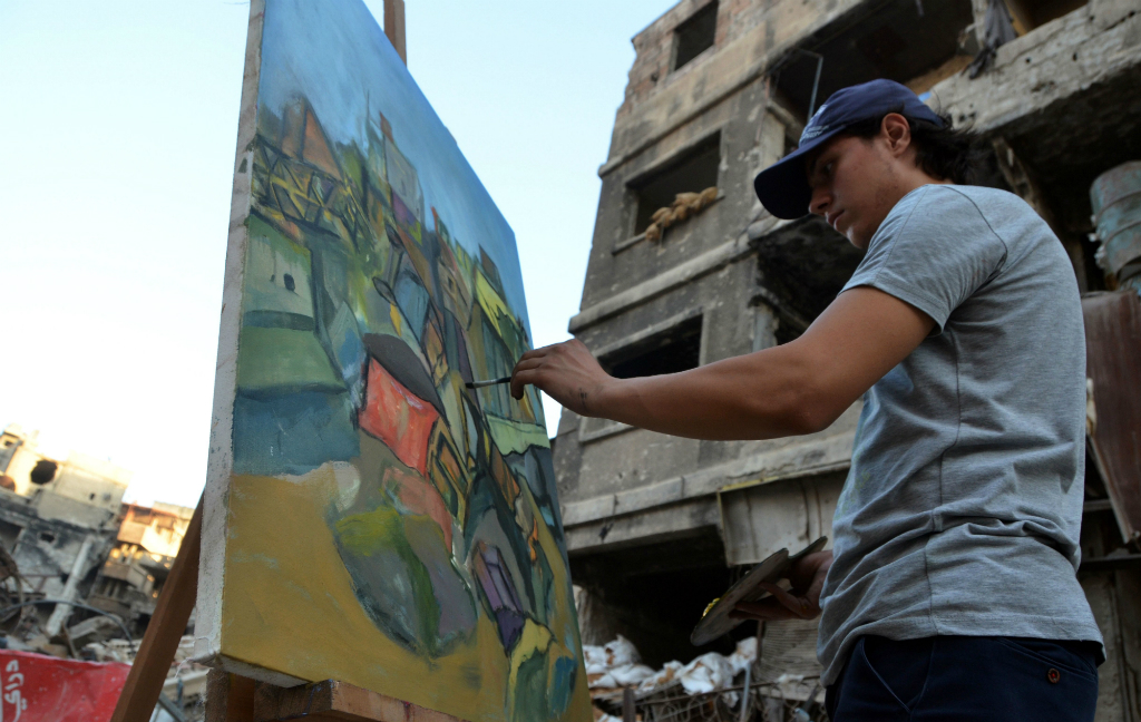 En medio de edificios derruidos, los jóvenes pintan con colores y lápices. Foto: AFP