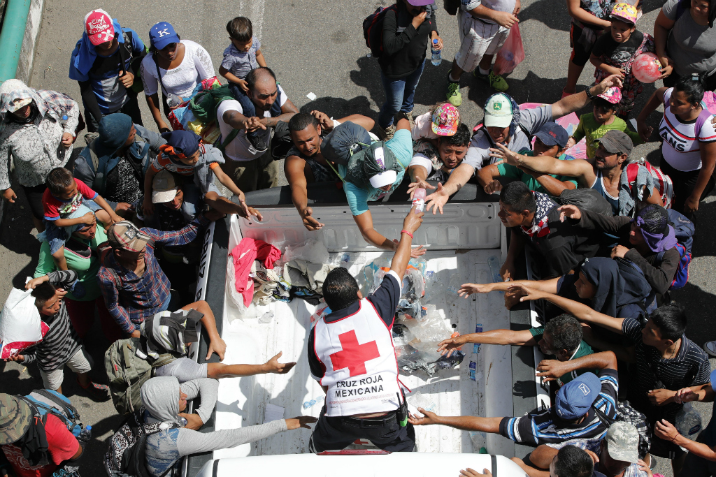 Personal de la Cruz Roja entrega agua a migrantes hondureños. Foto: EFE