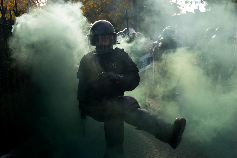 Un policía patea una bomba de humo que le lanzaron. Foto: AFP