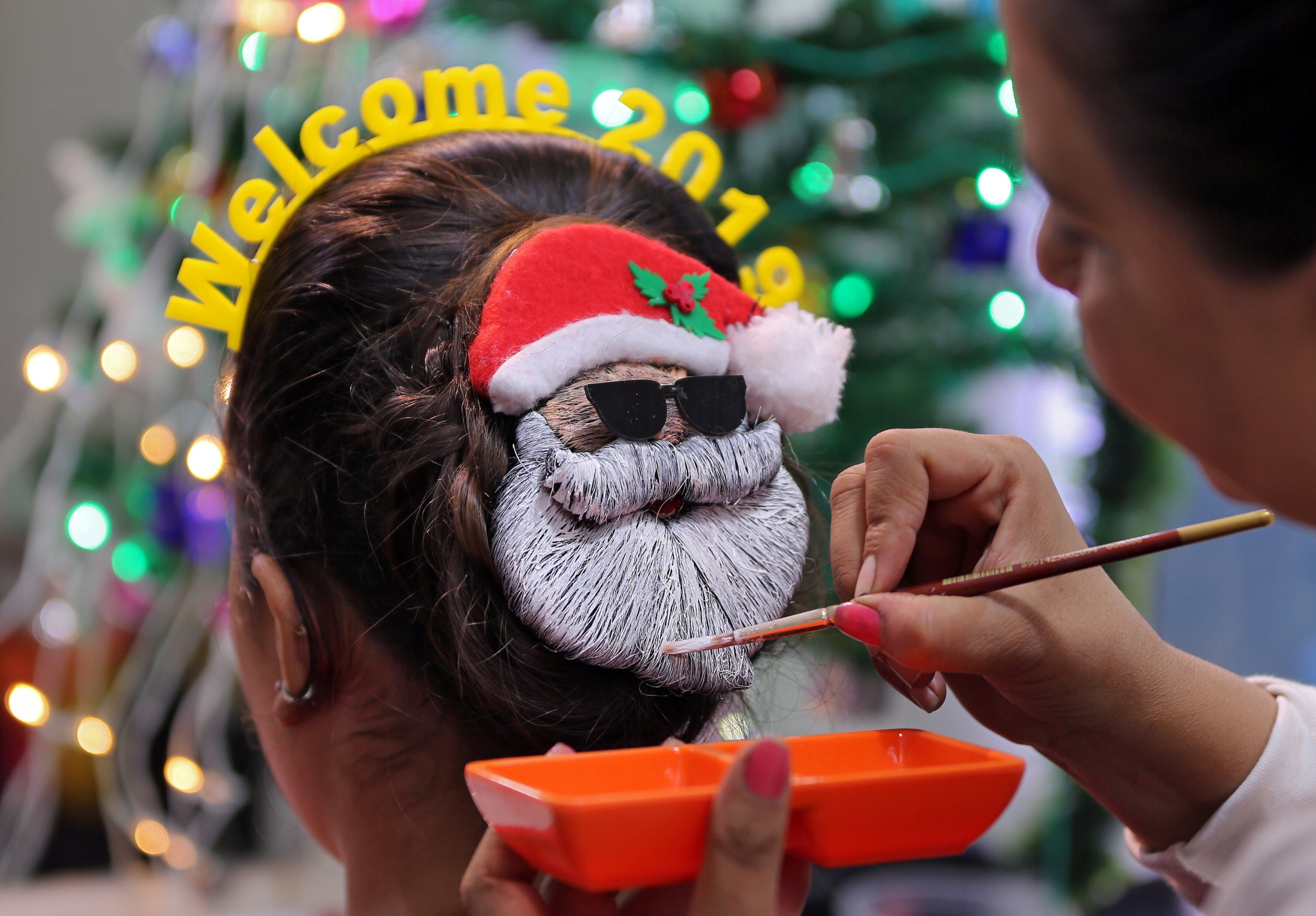 Una maquilladora decora el pelo de una mujer durante los festejos por la llegada del nuevo año en India. Foto: Reuters
