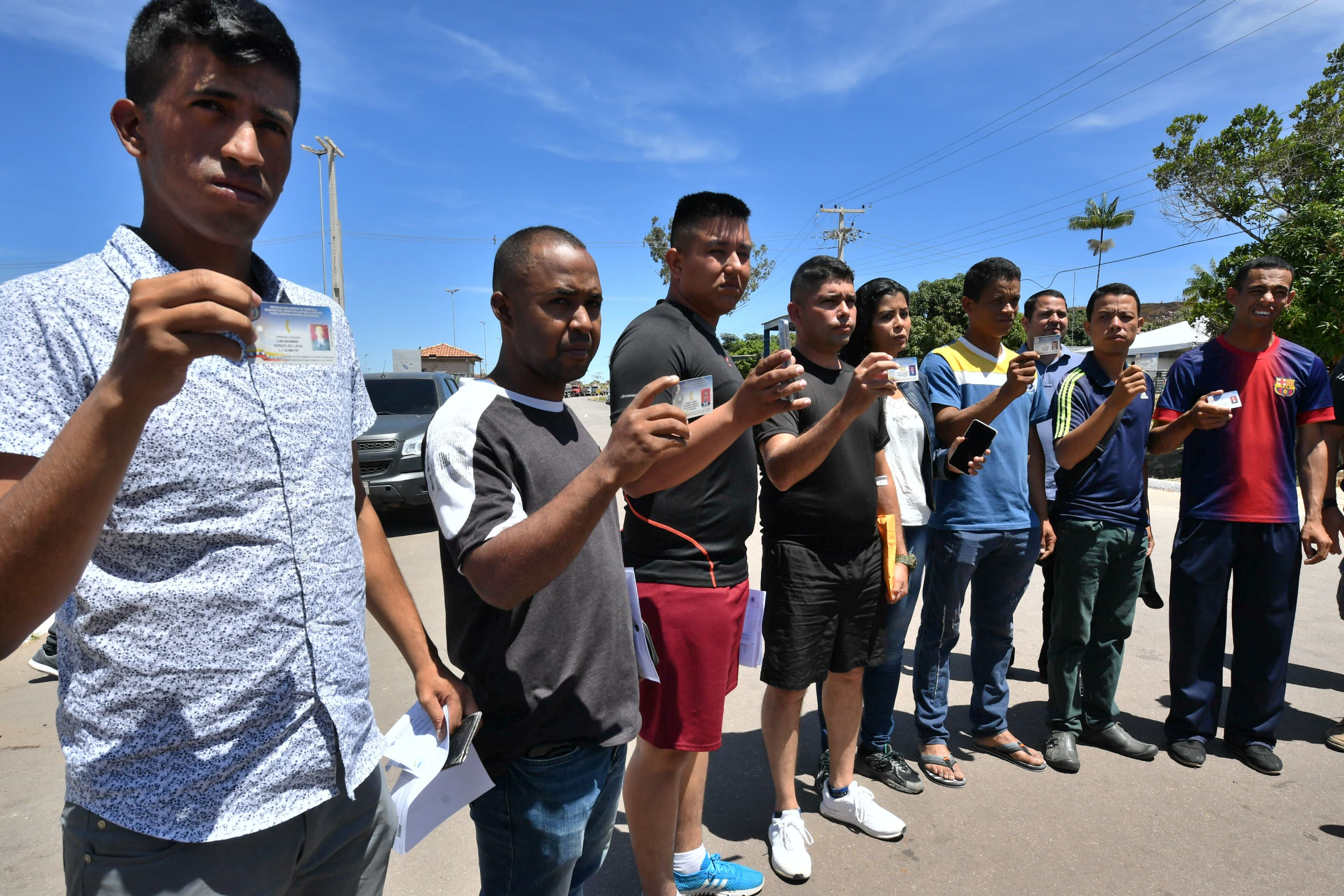 Soldados venezolanos muestran sus documentos tras buscar refugio en Brasil. Foto: AFP