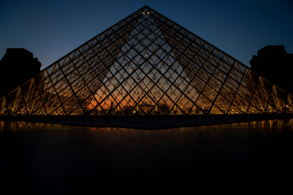 Puesta de sol detrás de la Pirámide del Louvre, en París. Foto: AFP.