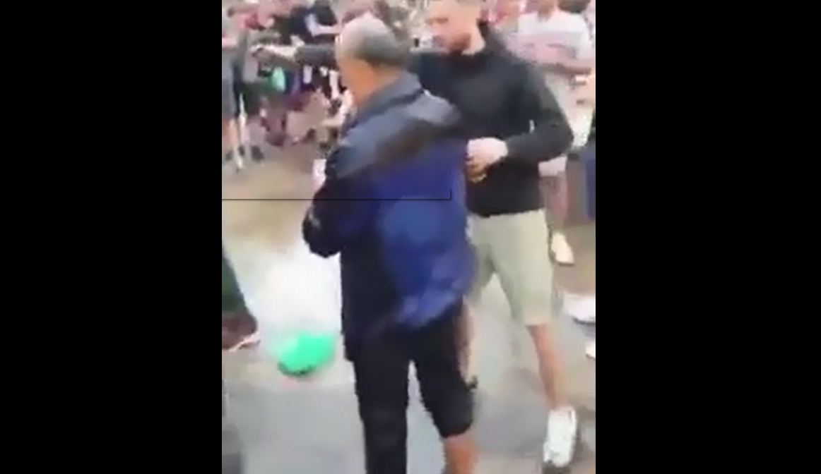 Un veterano hincha de Liverpool empuja a un turista asiático