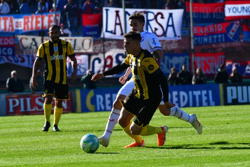 Giovanni González es seguido de cerca por Gabriel Neves en el clásico entre Nacional y Peñarol. Foto: Francisco Flores.