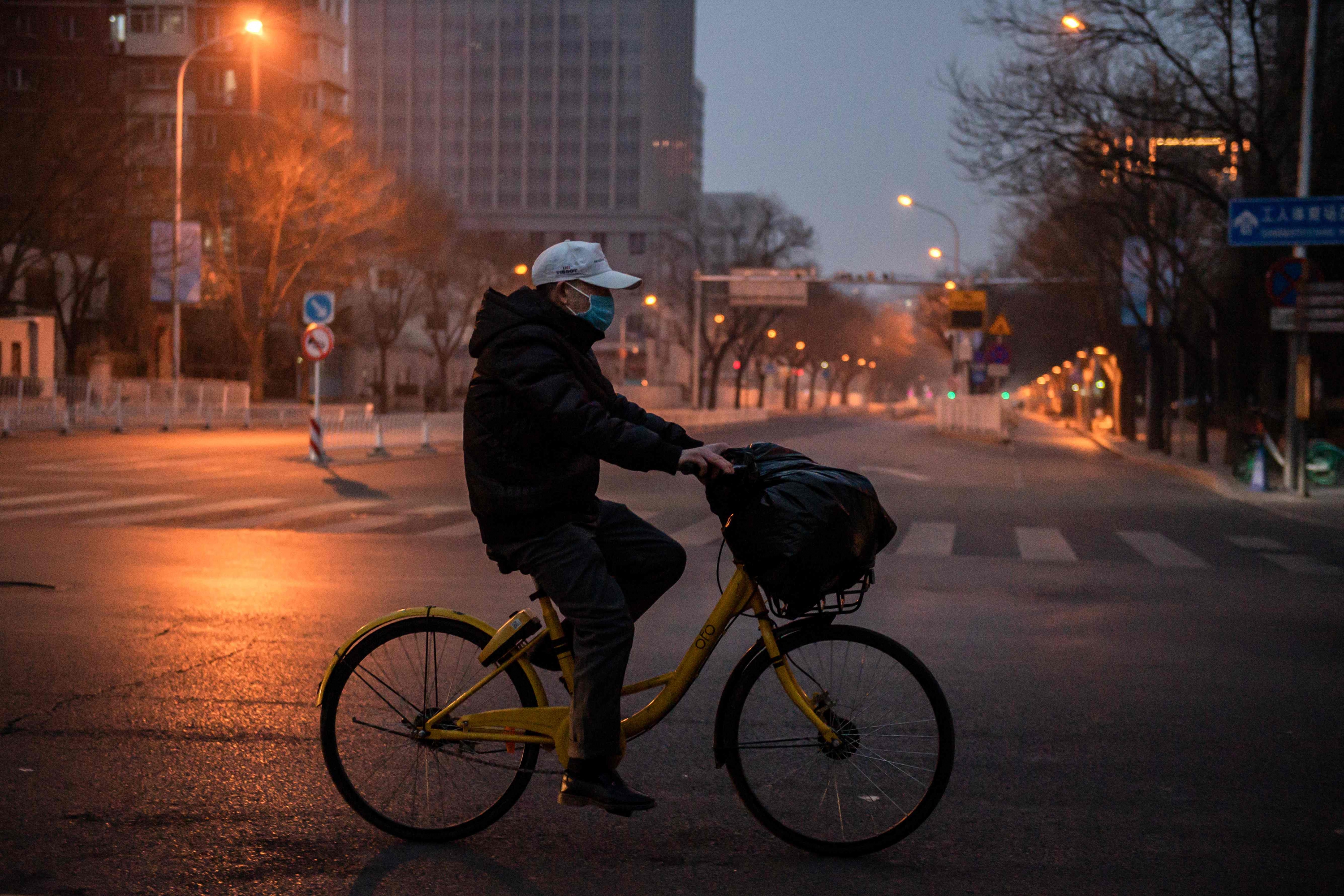 Hombre en bicicleta usa barbijo por el brote del coronavirus en Wuhan, China. Foto: AFP