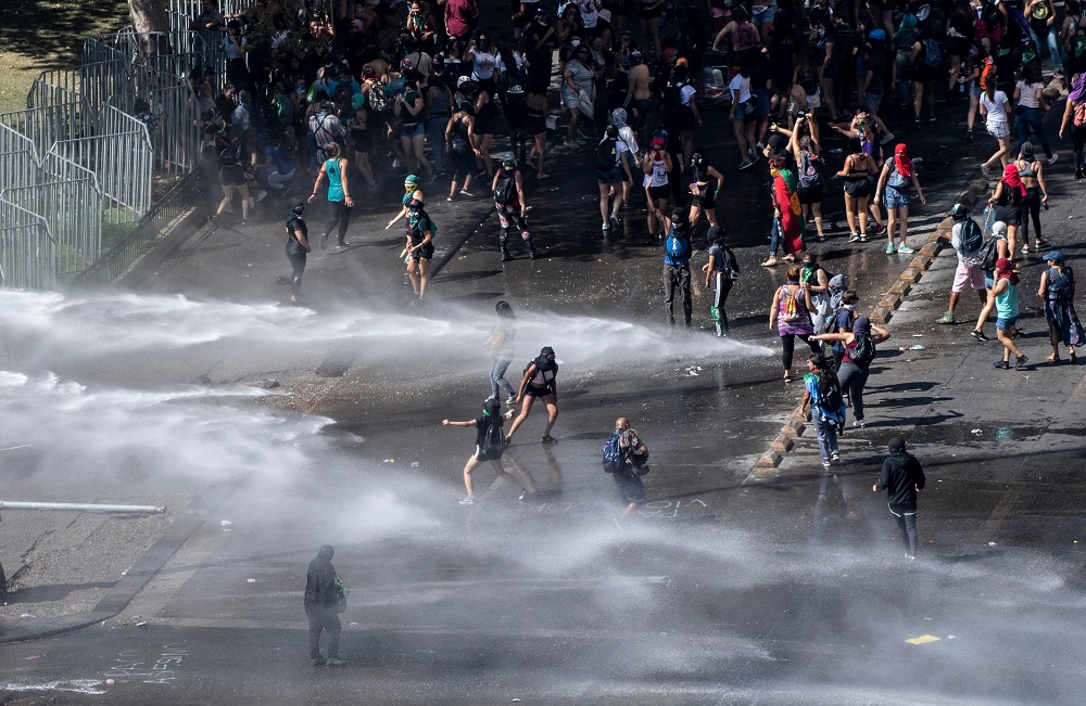 La policía antidisturbios reprime con tanques lanza agua a un grupo de jóvenes que tiraron las vallas frente al Palacio de la Moneda en Santiago de Chile. Foto: AFP