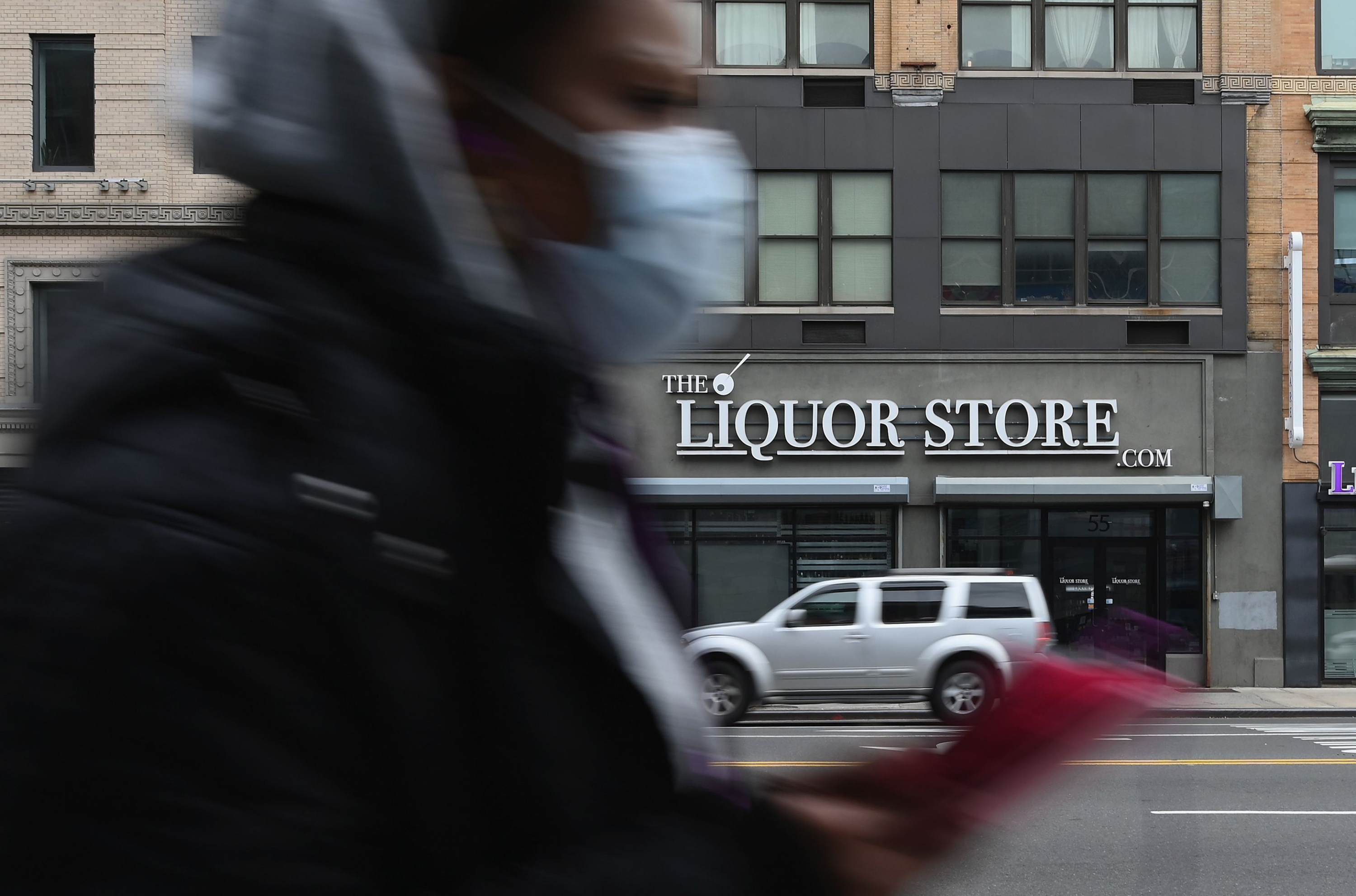 "Cuarentinis" en Nueva York. Una licorería frente a un peatón que usa barbijo por el coronavirus. Foto: AFP.