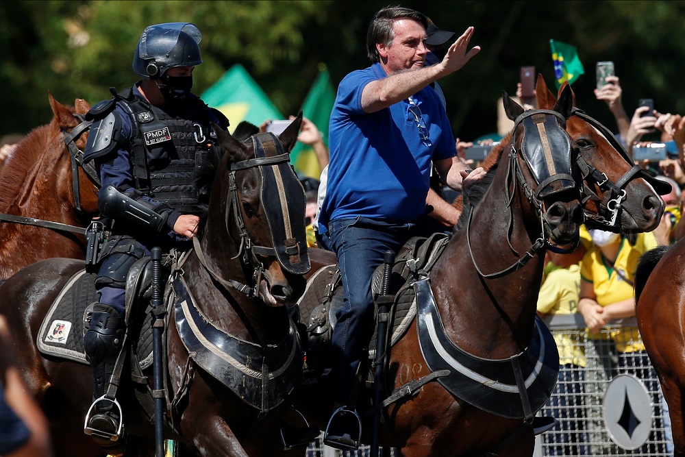 Jair Bolsonaro a caballo pasando frente a un grupo de simpatizantes que cada domingo se reúnen a las afuera de la sede de gobierno en Brasilia. Foto: Reuters