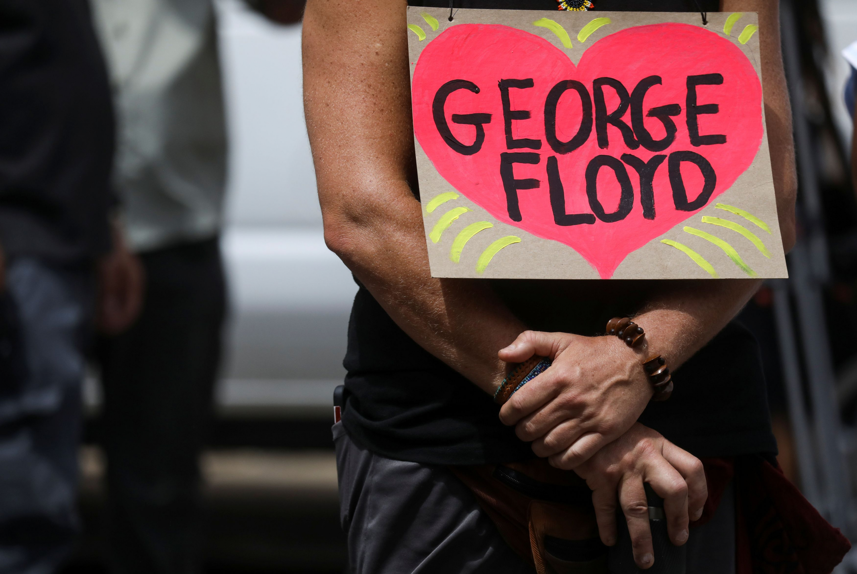 Una persona sostiene una pancarta este jueves afuera del lugar donde se realiza el funeral de George Floyd. Foto: Reuters