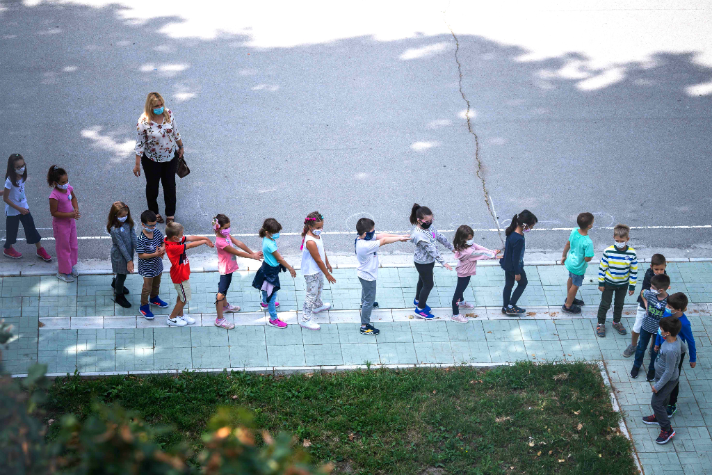 Niños con tapabocas toman distancia antes de ingresar a una escuela. Foto: AFP