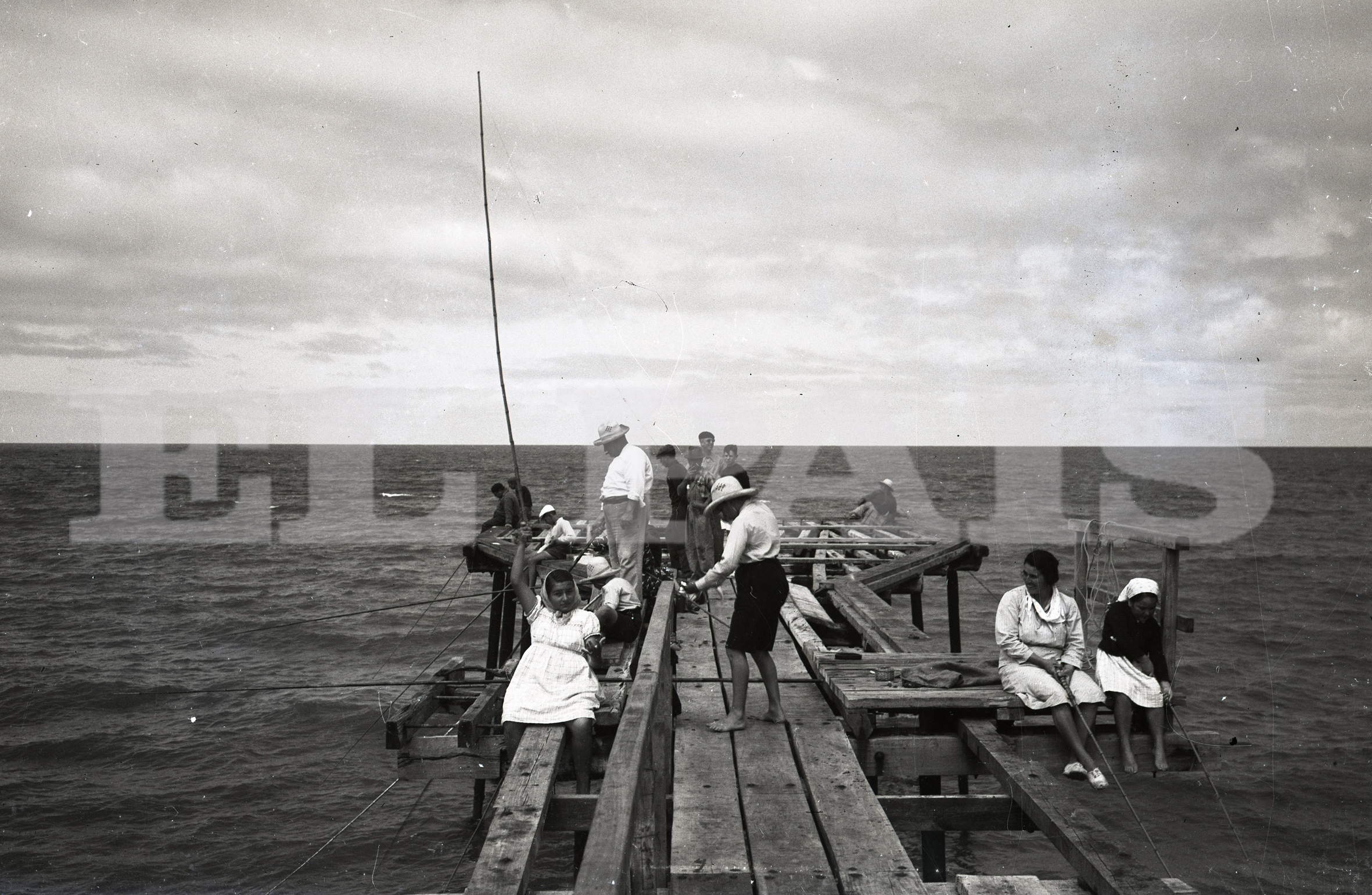 Mujeres y hombres comparten el muelle de pesca de Las Delicias, década de 1940. Foto: Archivo El País.