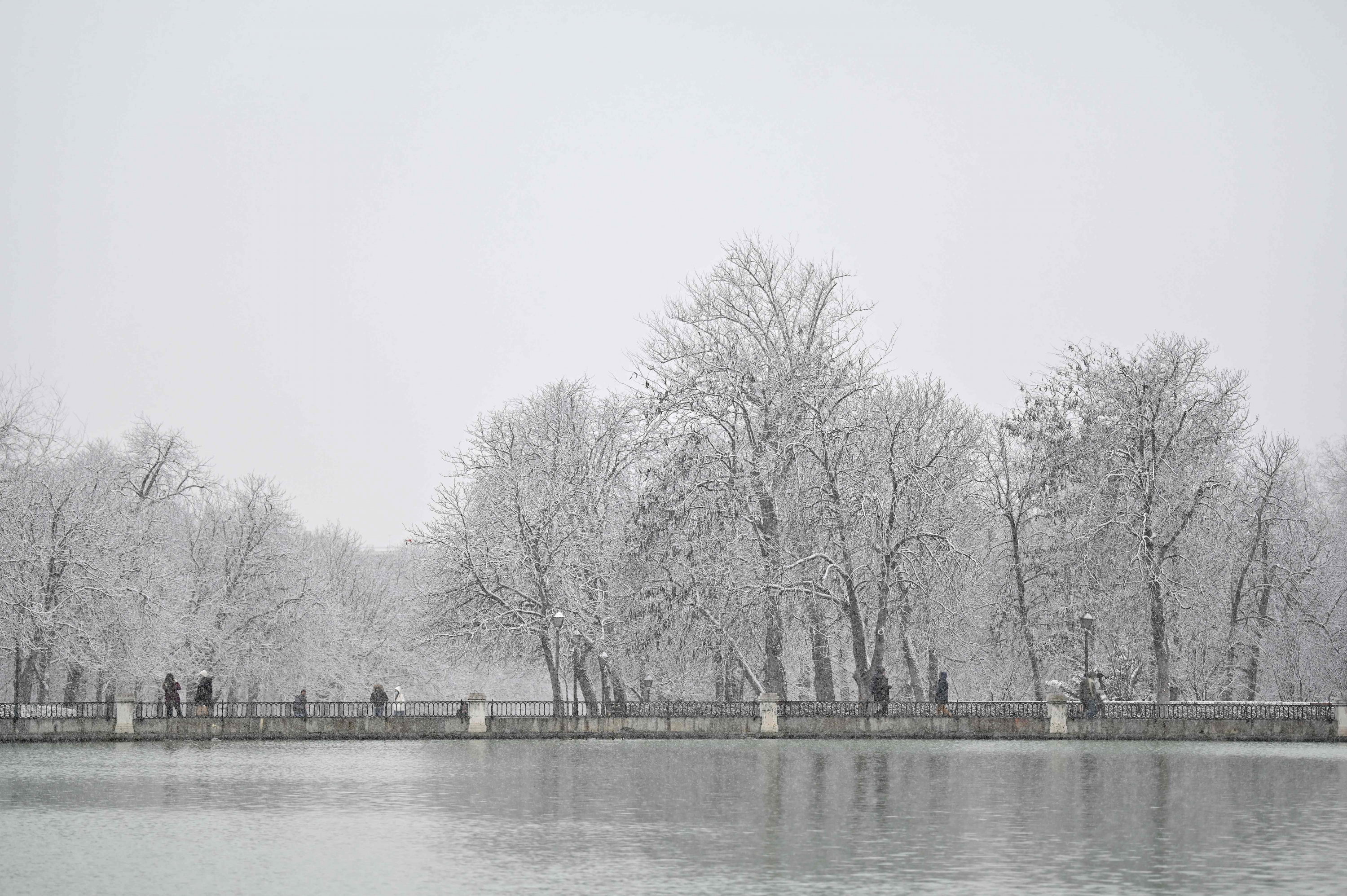 Personas caminan mientras cae la nieve en el Parque del Retiro, en el centro de Madrid. Foto: AFP