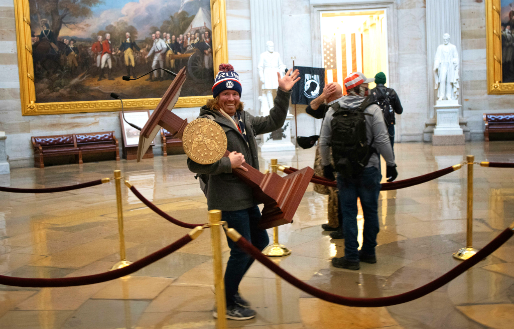 Uno de los militantes que asaltó la sede del Congreso roba la tarima desde la cual habla Pelosi. Foto: AFP