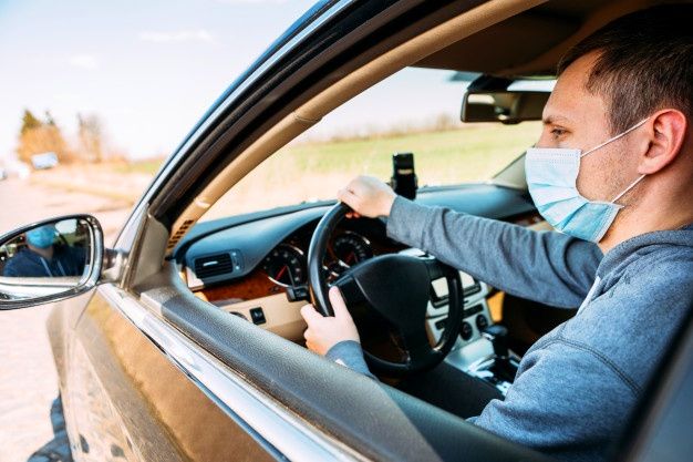 Hombre con tapabocas conduciendo un auto. Foto: Shutterstock