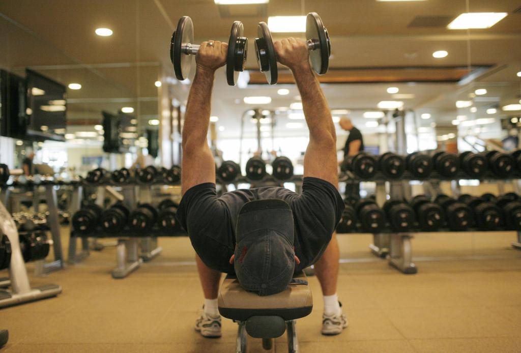 Hombre levanta pesas en un gimnasio. Foto: AFP.