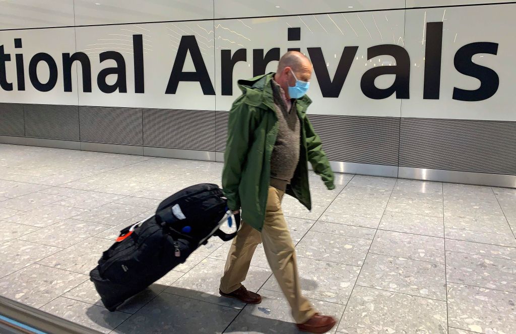 Hombre con tapaboca caminando por un aeropuerto. Foto: AFP