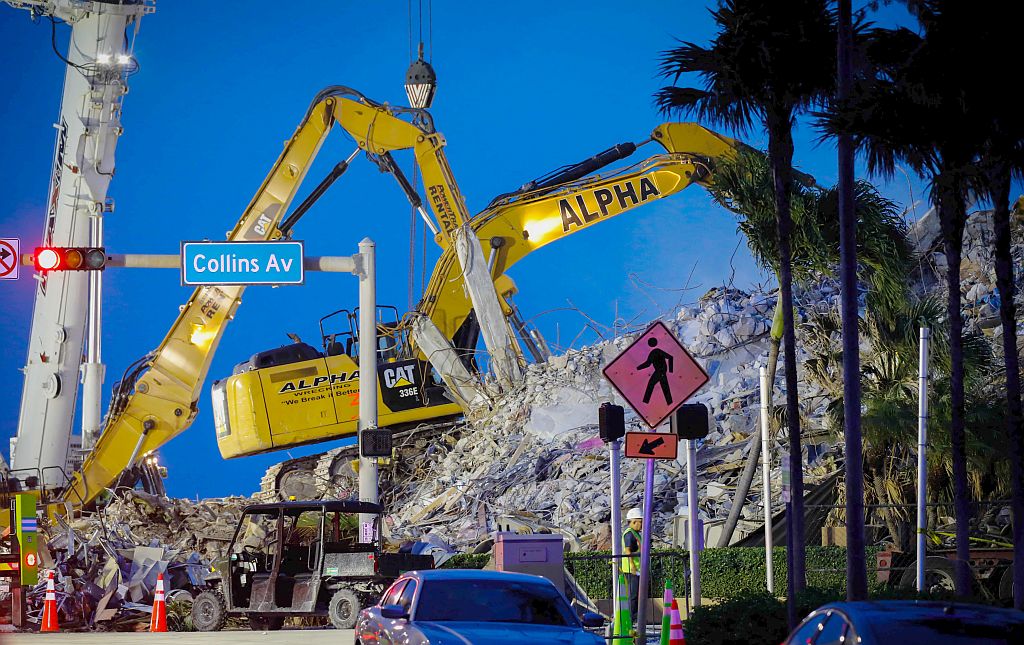 Una máquina retroexcavadora trabaja en los escombros del edificio derrumbado en Miami. Foto: AFP
