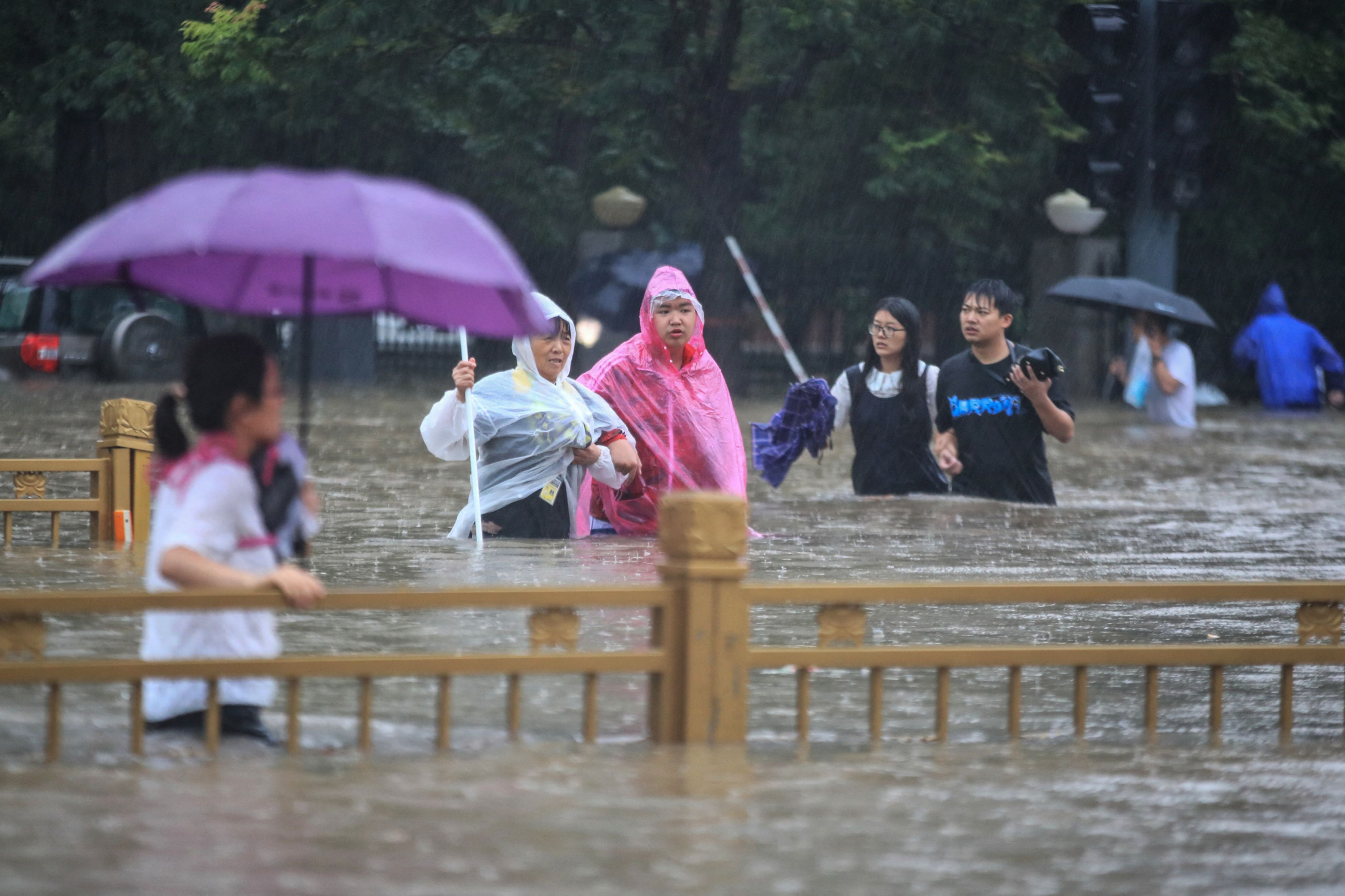 Personas caminando por calles inundadas en China. Foto: AFP