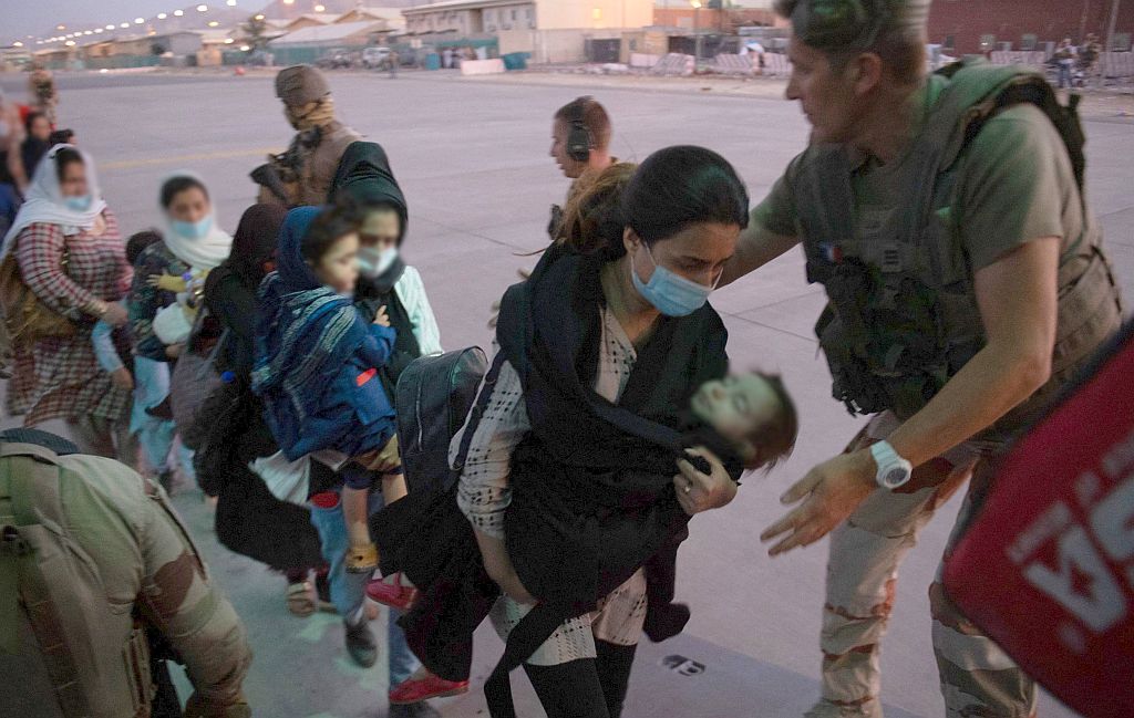 Familias afganas son subidas a bordo de un avión militar en el aeropuerto de Kabul. Foto: AFP