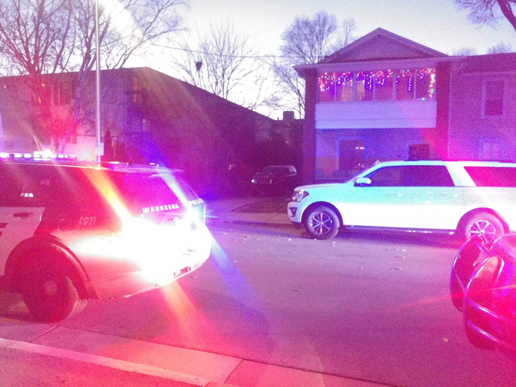 Autos de policía estacionados cerca de un SUV rojo abollado que pudo haber sido el involucrado en el incidente del desfile navideño. Foto: AFP