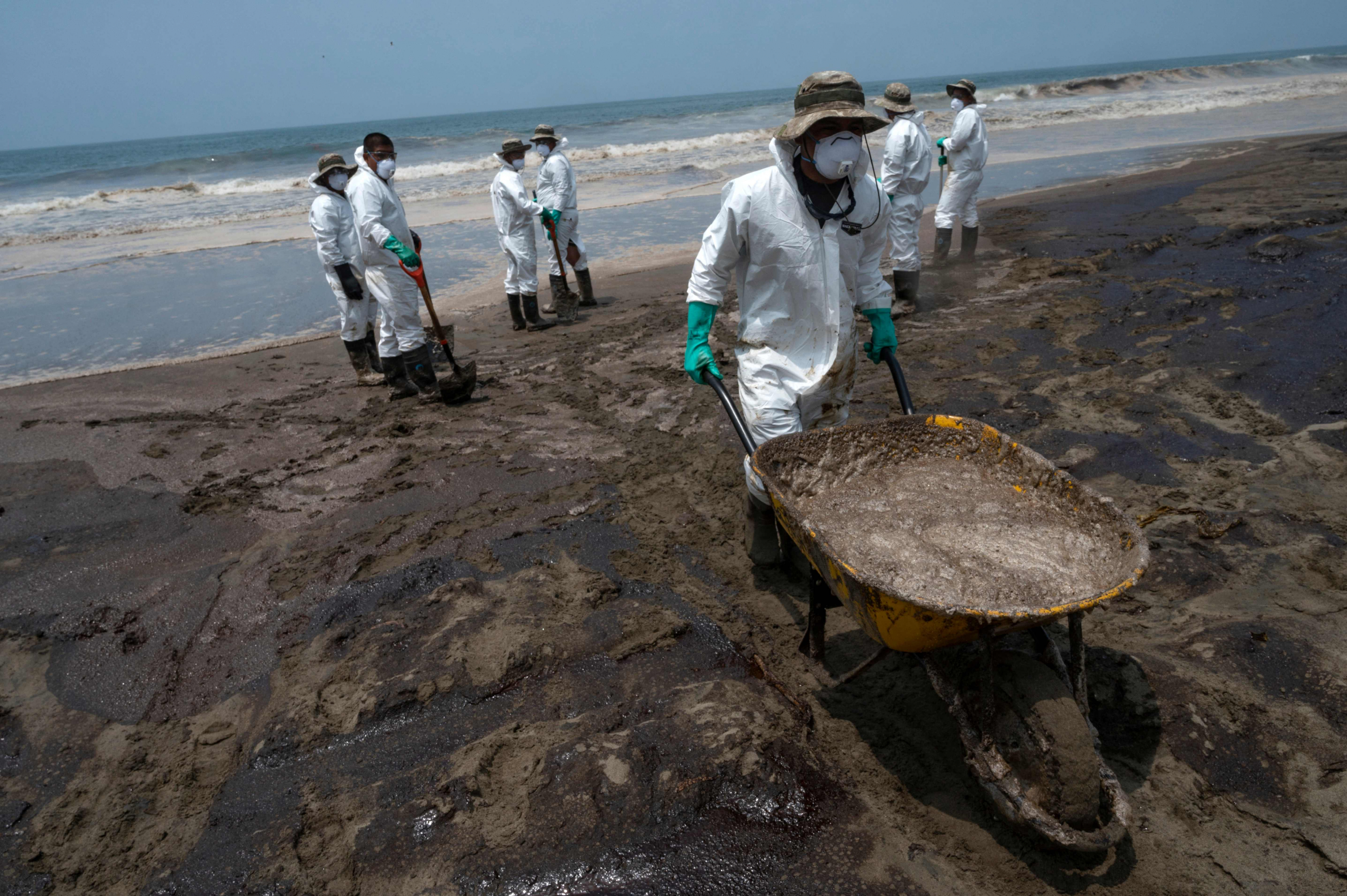 Miembros del Ejército peruano retiran petróleo arrastrado a tierra en la playa Chacra y Mar, cerca de Huaral, Perú. Foto: AFP.
