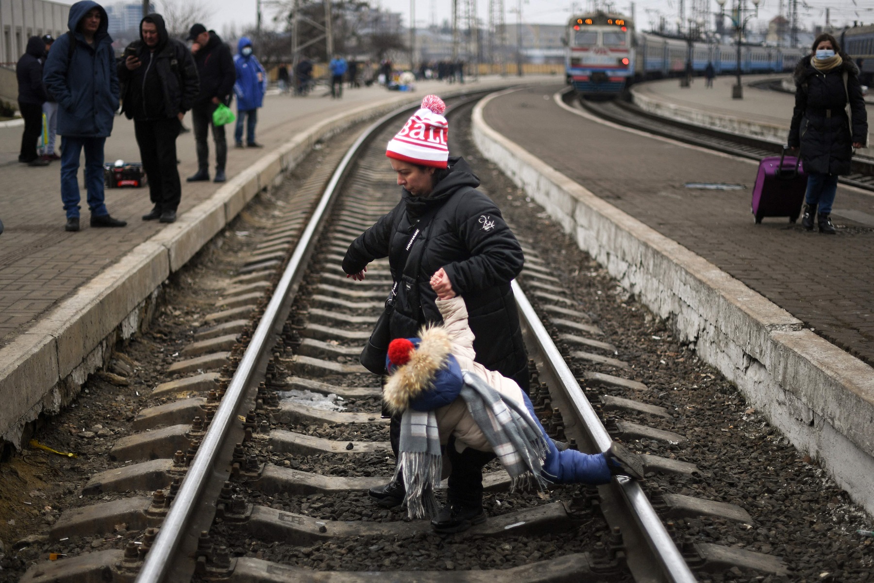 Mujer con un niña corriendo por una vía de tren. Foto: AFP.
