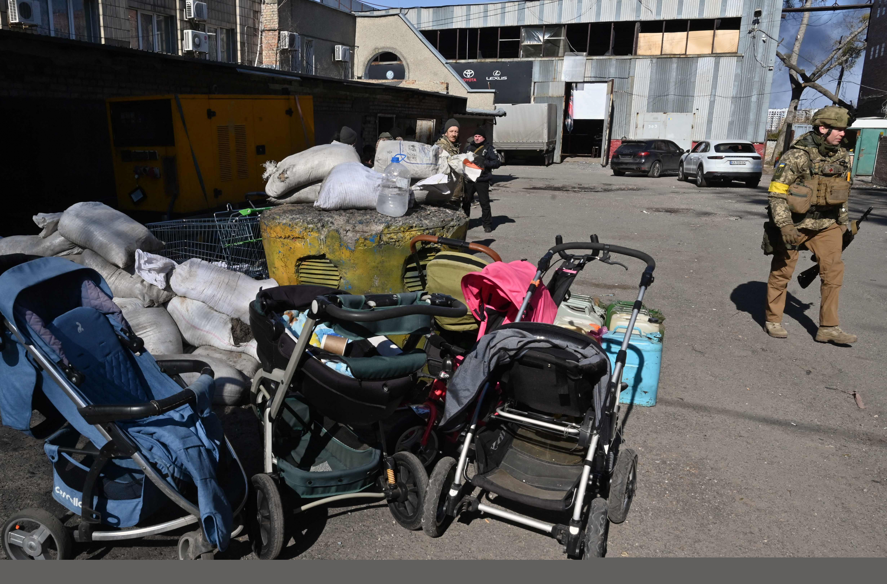 Un soldado ucraniano pasa junto a cochecitos abandonados en Irpin, al norte de Kiev. Foto: AFP.