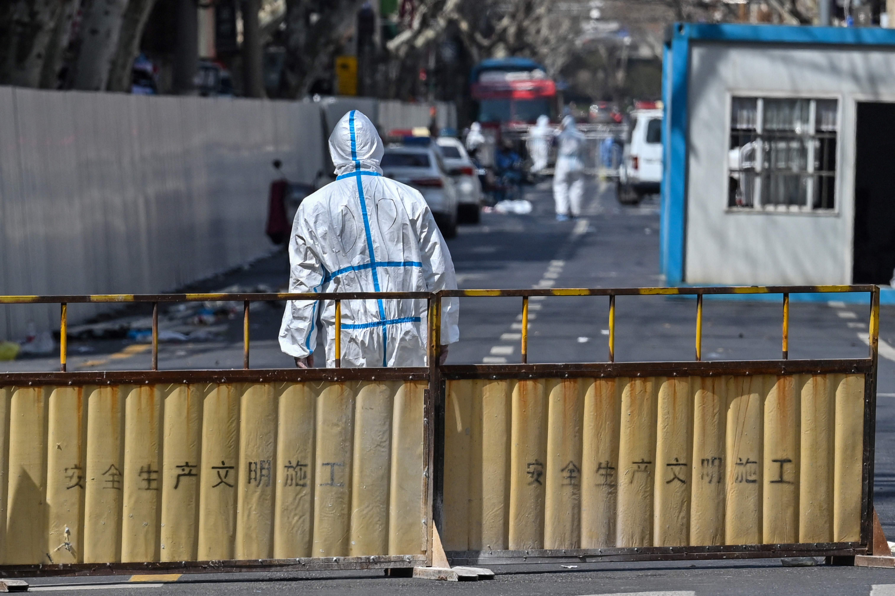 Un funcionario se encuentra en una barrera en una calle cerrada luego de la detección de nuevos casos de Covid-19 en el área de Shanghái. Foto: AFP