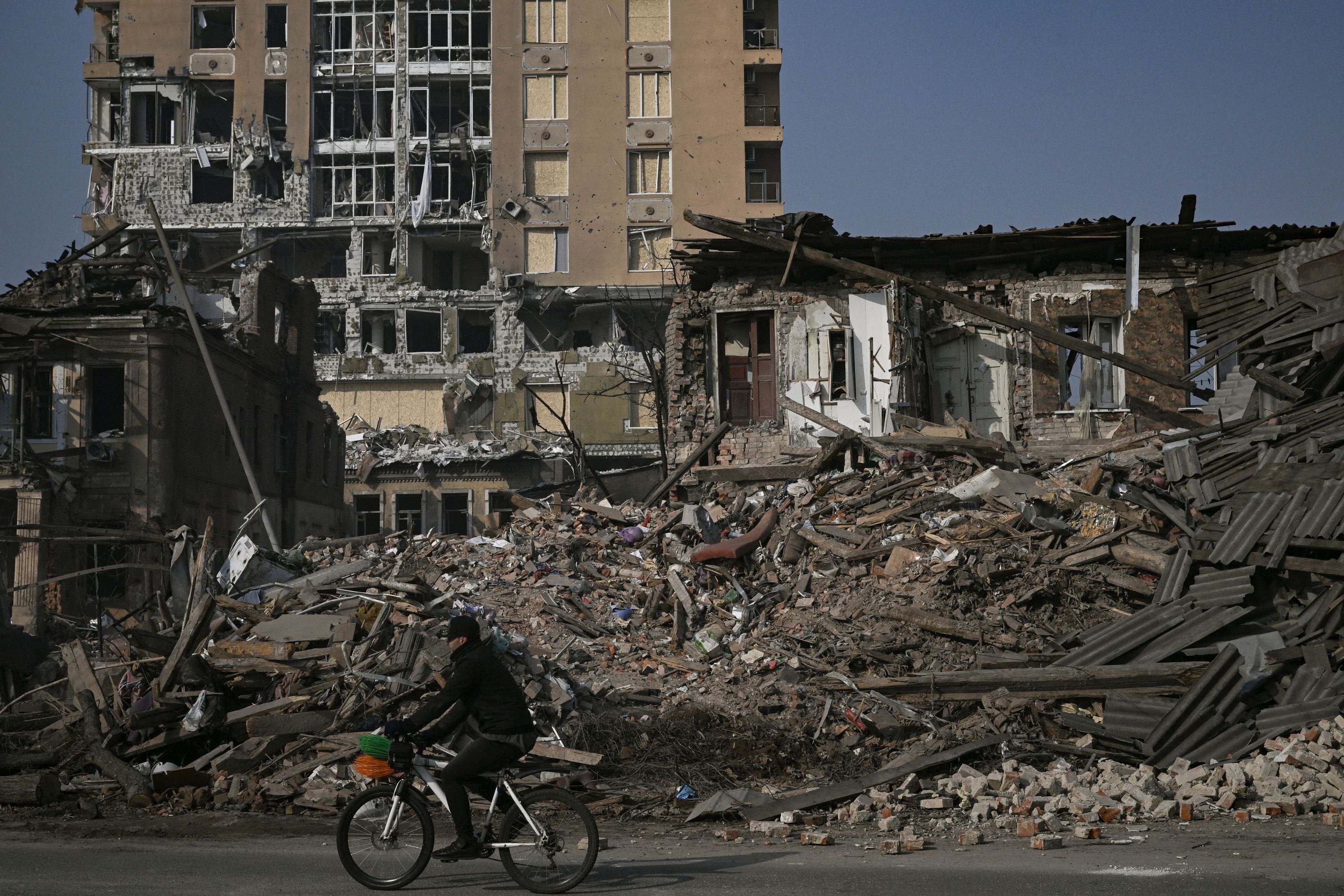 Un ciclista pasa junto a las casas destruidas por los bombardeos en Járkov. Foto: AFP.