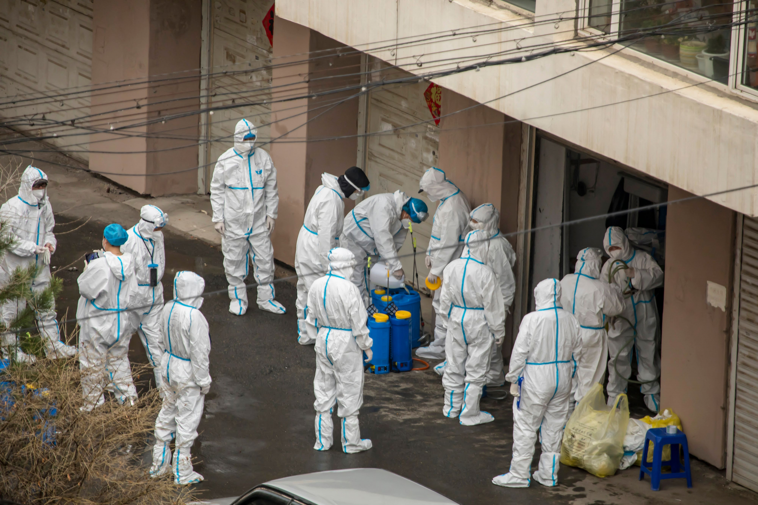Personas que usan equipo de protección personal se preparan para rociar desinfectante en un área residencial en Jilin, en China. Foto: AFP.