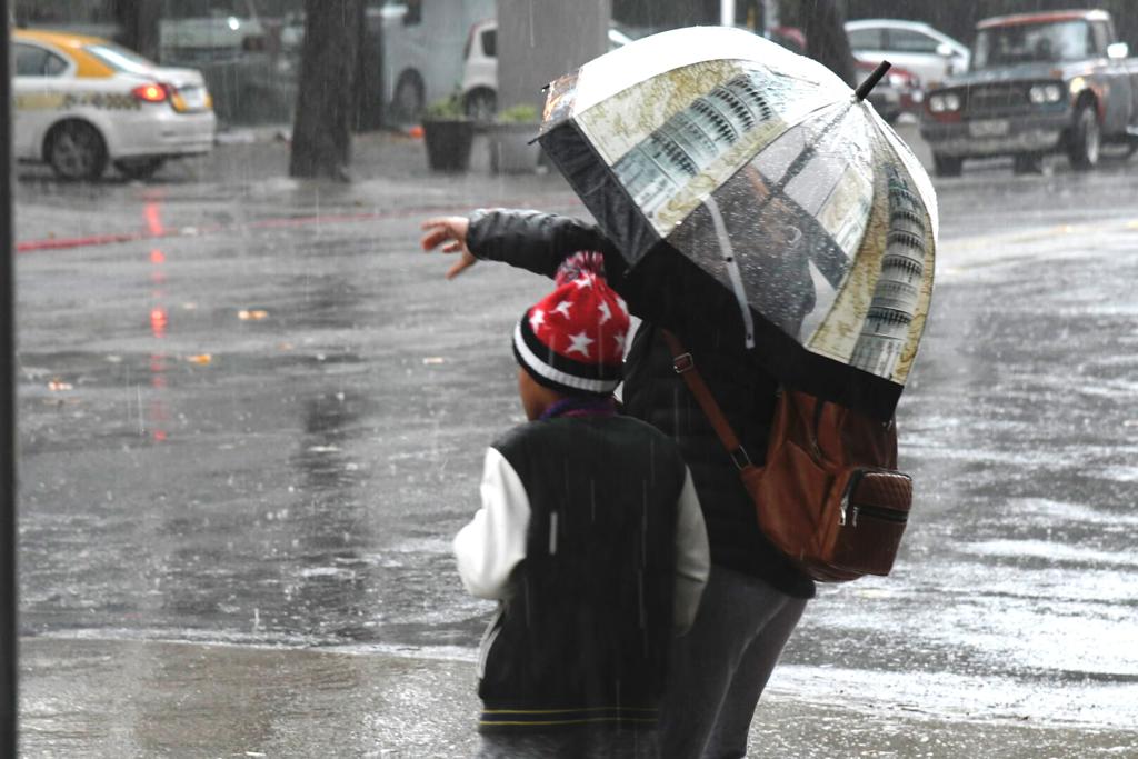 Personas se protegen con paraguas del viento y la lluvia. Foto: Leonardo Mainé