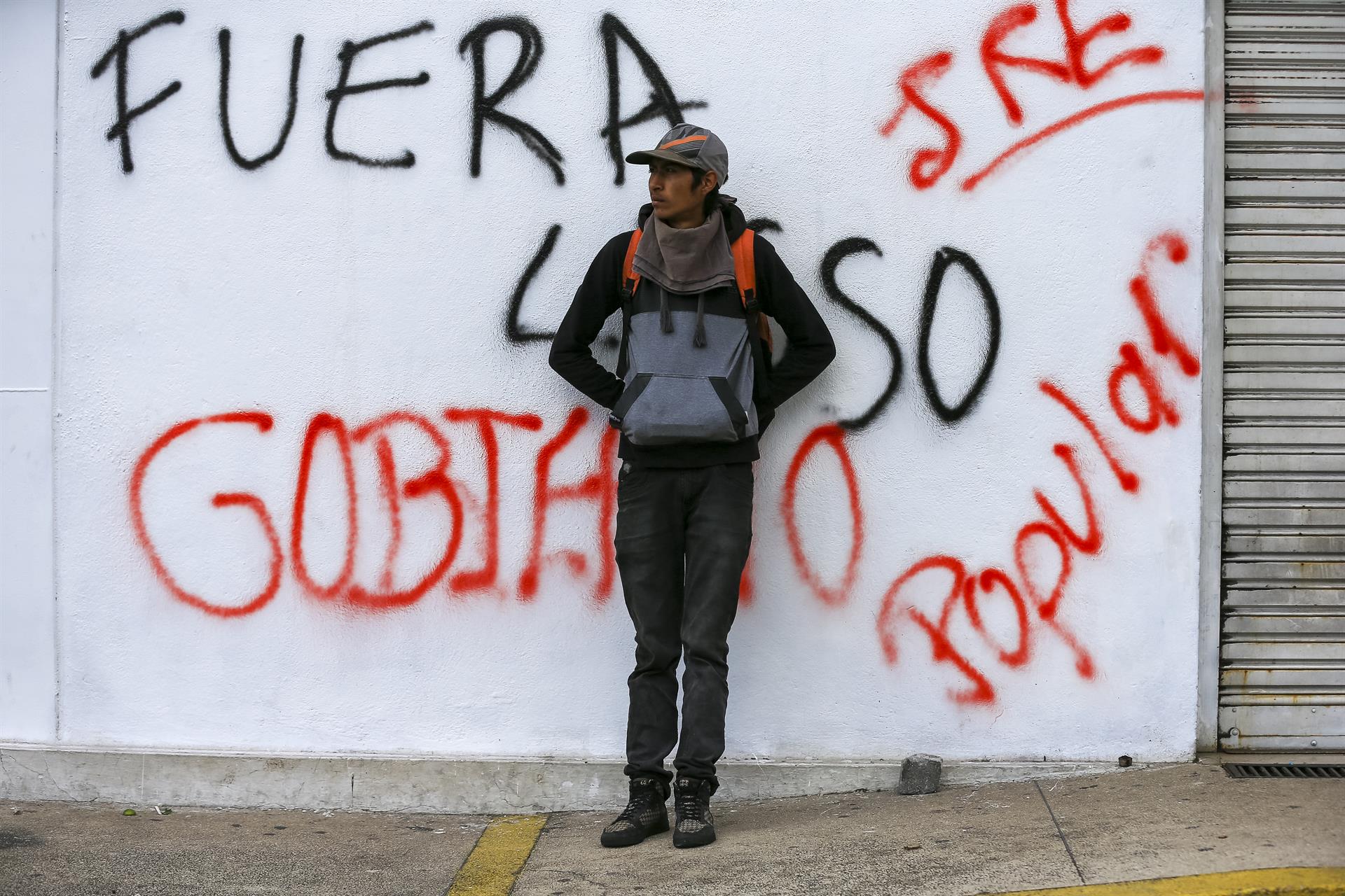 Un hombre sobre un muro pintado en contra del presidente de Ecuador. Foto: EFE