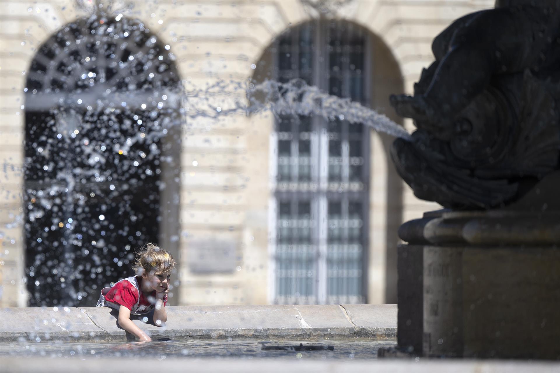 Ola de calor en Europa. Un niño se rocía con agua de la fuente en la Place de la Bourse, en la ciudad francesa de Burdeos. Foto: EFE