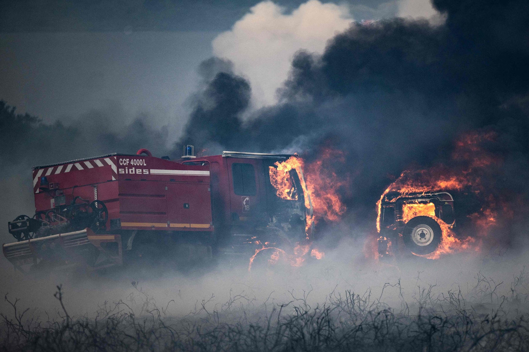 Camiones de bomberos ardiendo tras incendio forestal. Foto: AFP.