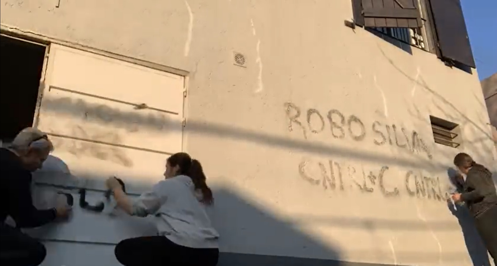 Robert Silva limpiando junto a su familia en graffiti que pintaron en la fachada de su casa como protesta a la reforma educativa. Foto: (Captura) Twitter
