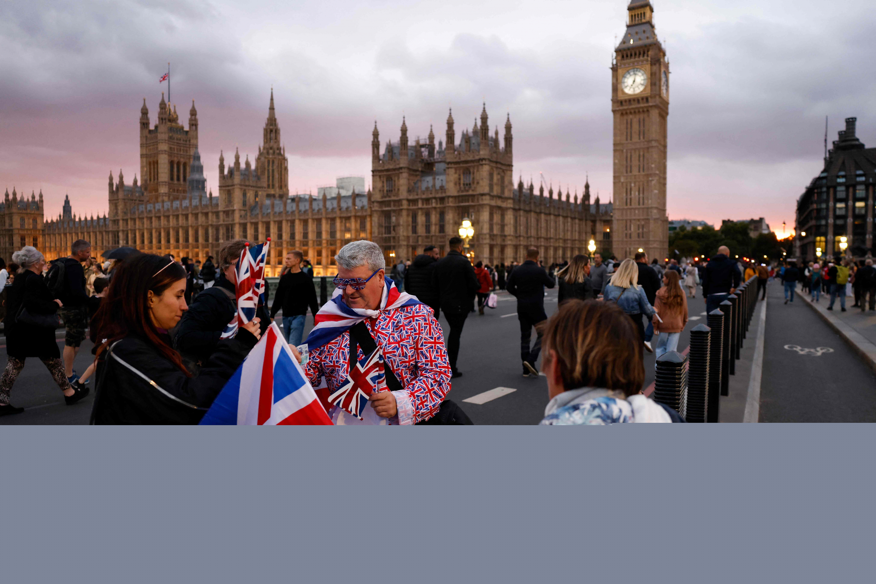 Un vendedor ambulante vende banderas Union Jack a los simpatizantes en el puente de Westminster en Londres, en la previa del funeral de Isabel II. Foto: AFP